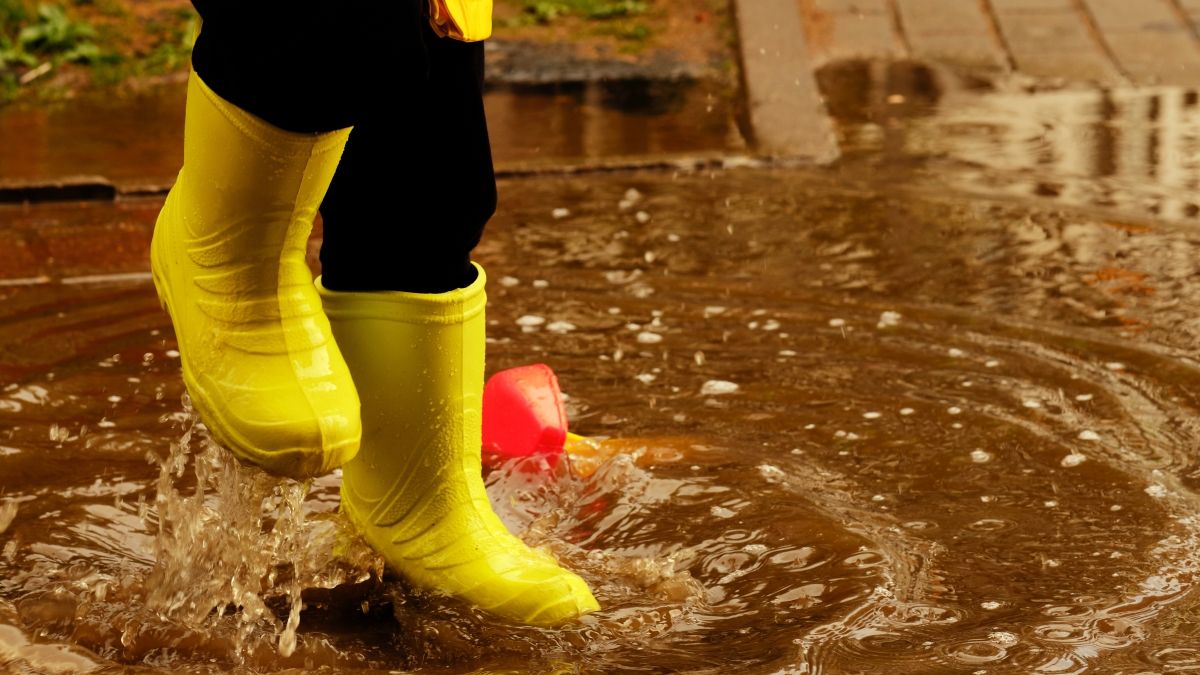 child with yellow boots jumping in puddle