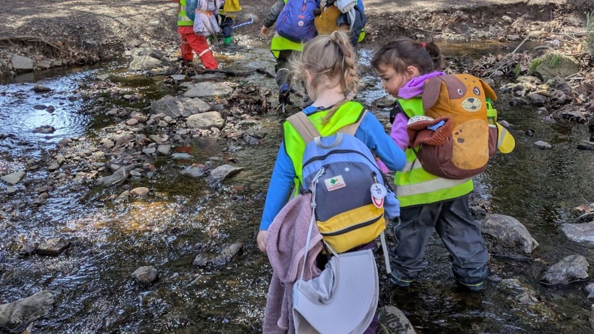 children in line walking through forest