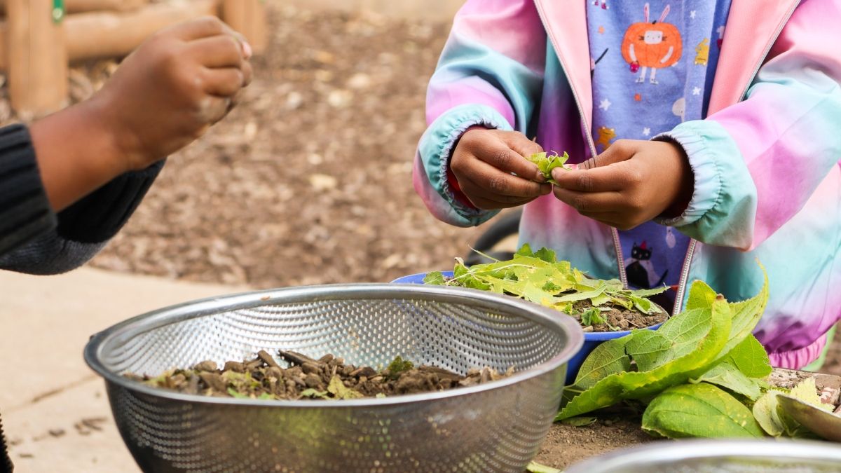 child's hands playing in mud kitchen