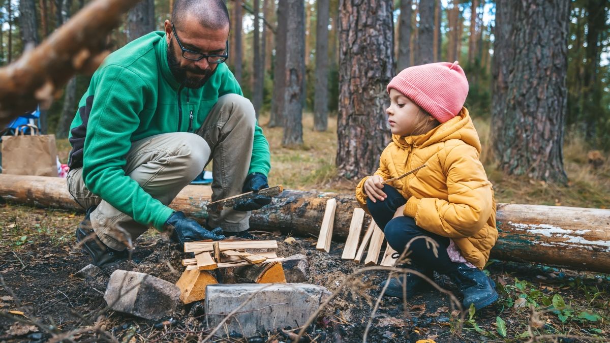 father and daughter constructing campfire