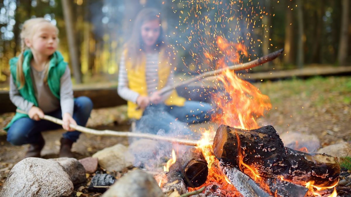 sisters roasting hotdogs over campfire