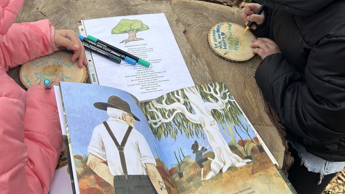 children outside reading a children's book and doing a craft