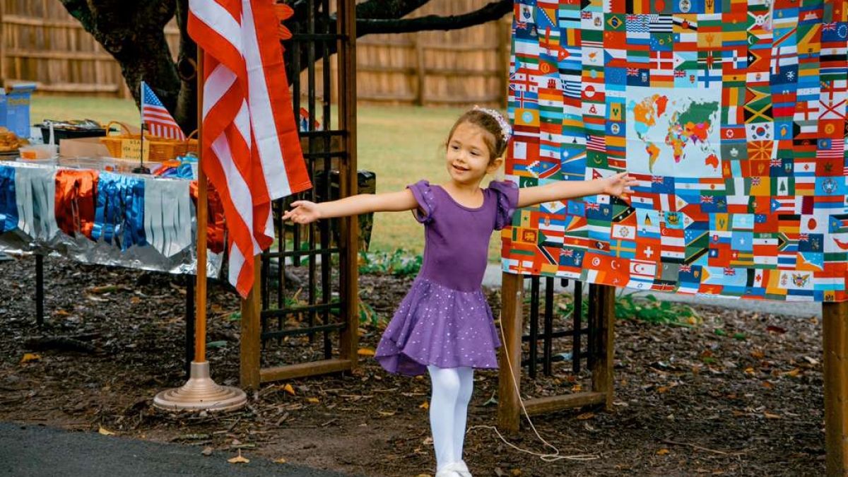 Child standing in front of multicultural display with arms open wide