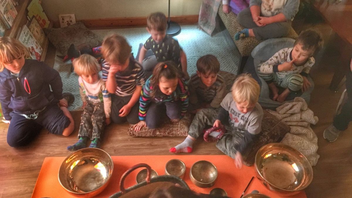 young children sitting in front of a bunch of sound bowls