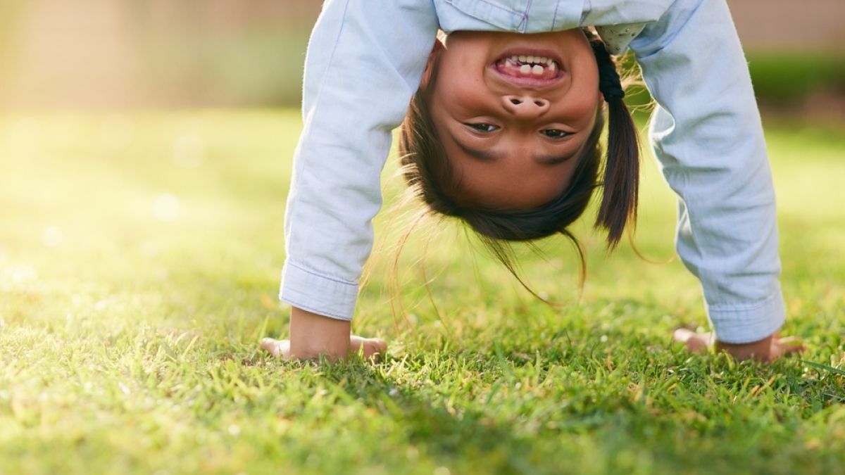 Happy, girl and handstand with grass in park