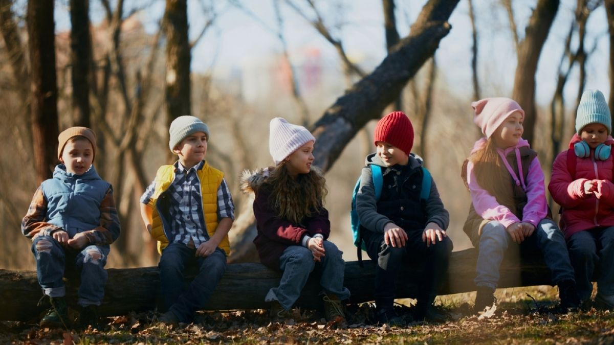 Row of kids, classmates perched on a log