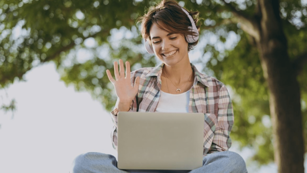 person waving to laptop screen