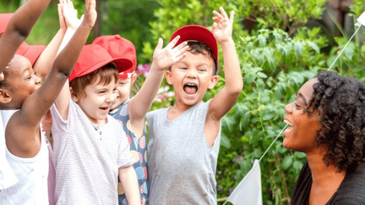 children expressing enthusiasm toward teacher kneeling next to them