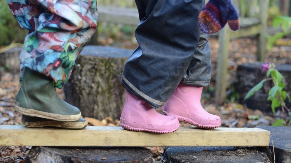nature preschoolers with rain boots on feet balancing