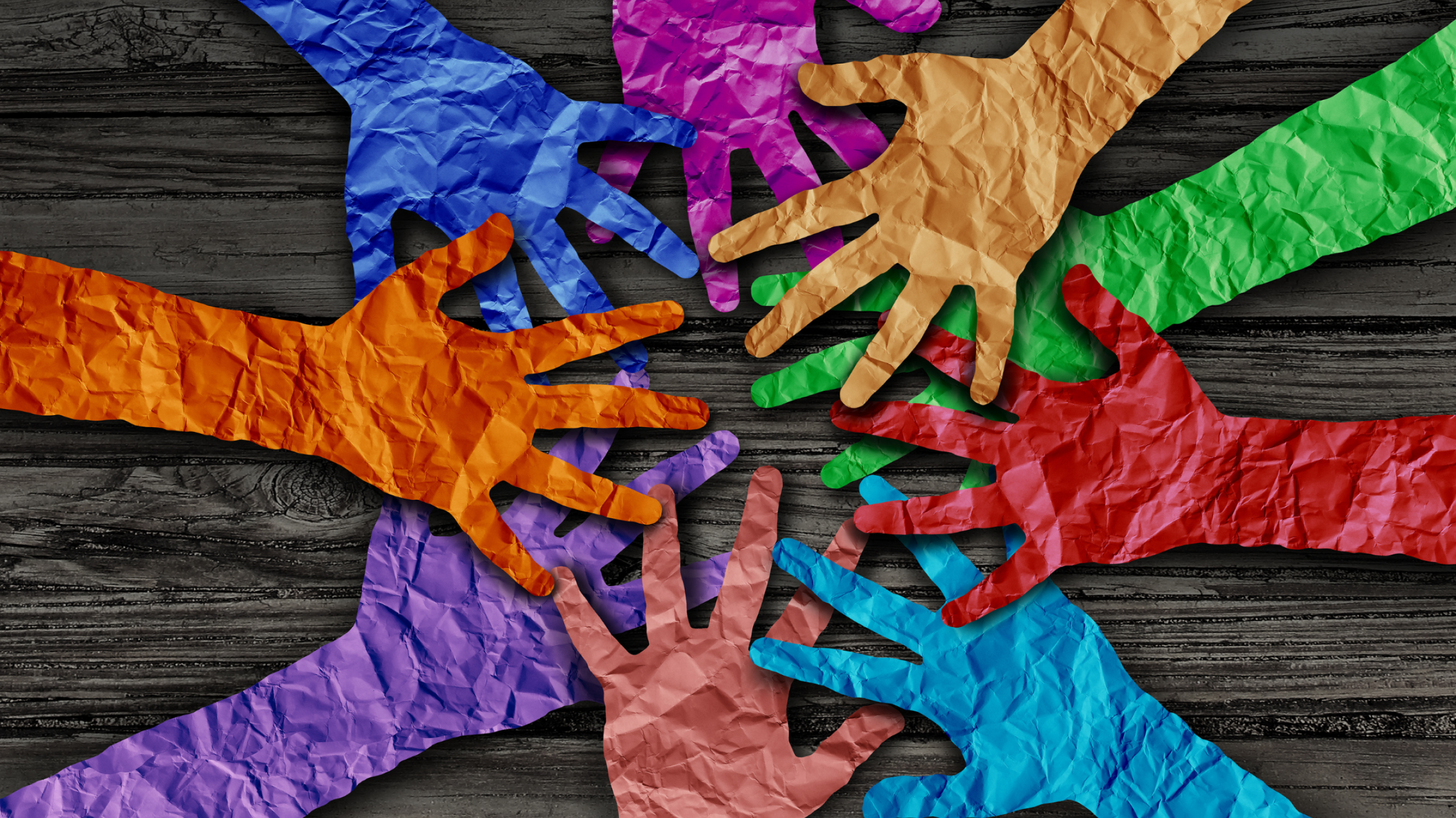colorful paper hands reaching toward center of table