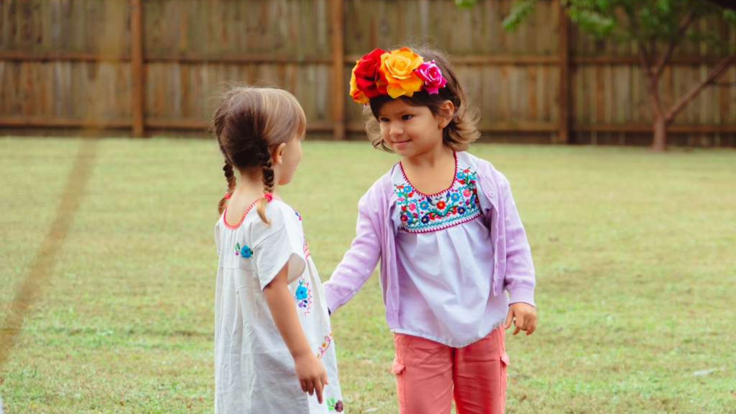 two children in cultural attire holding hands in nature