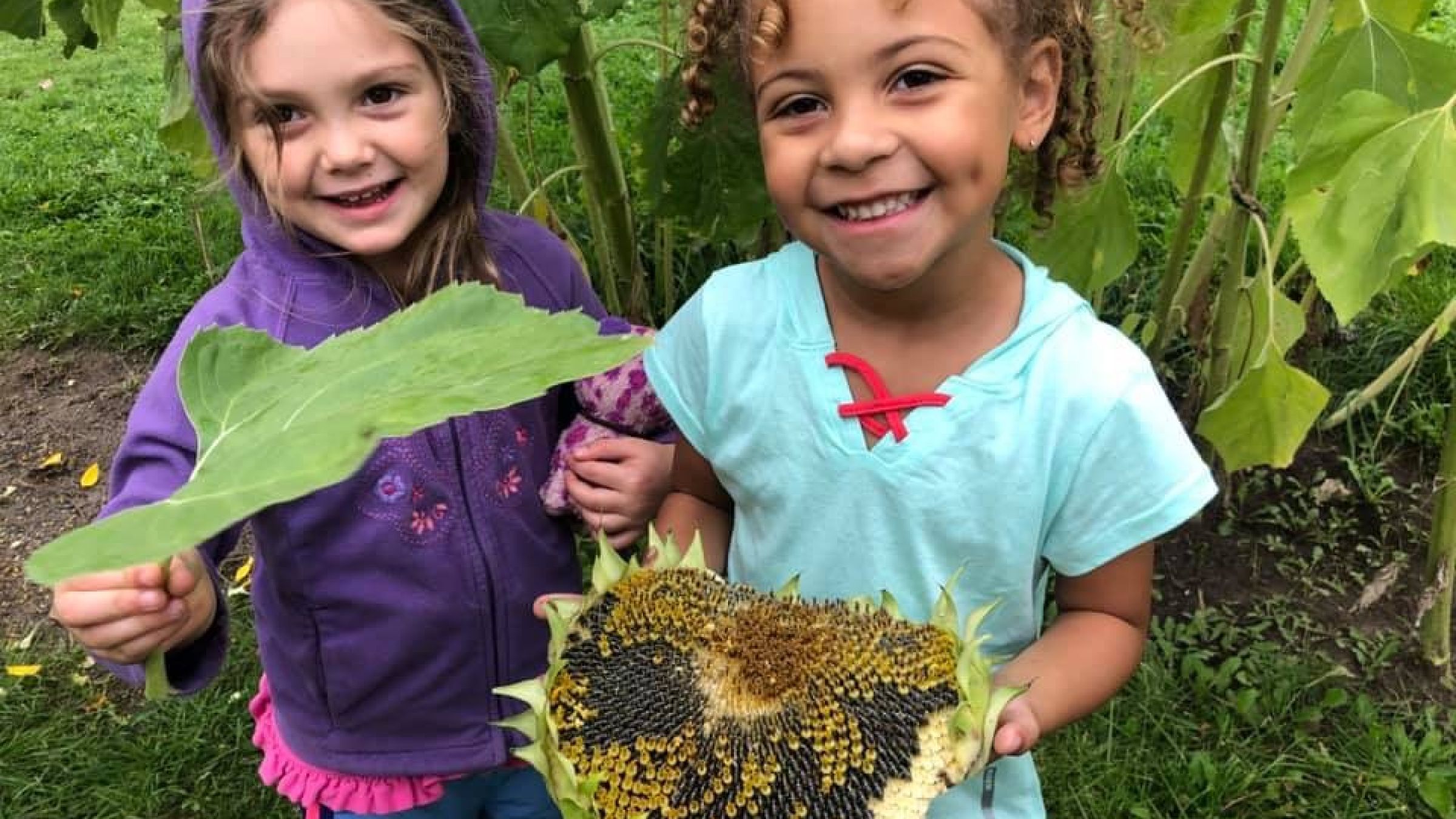 two children showing off plants in the garden