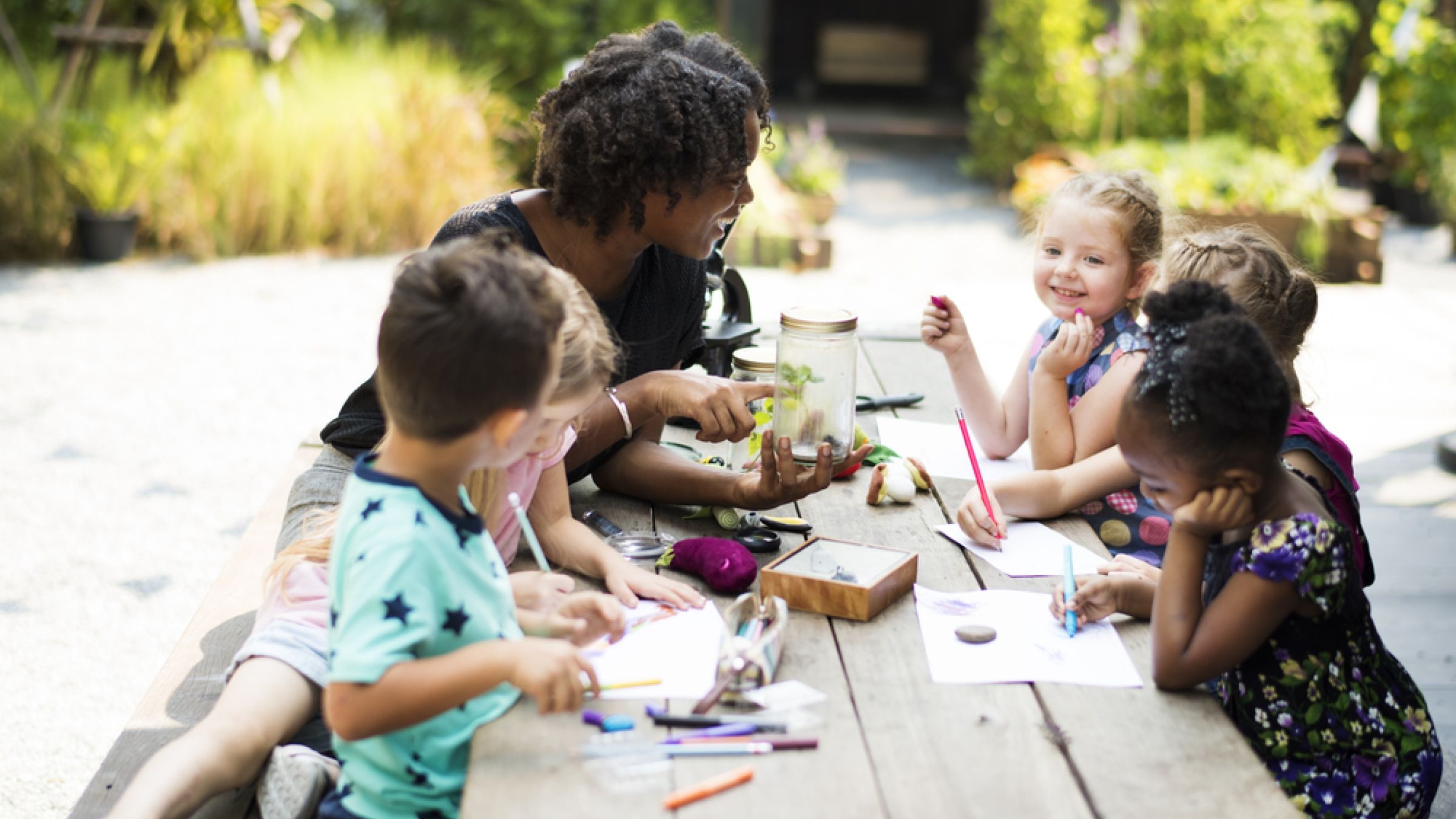 educator with group of young children outside doing artwork