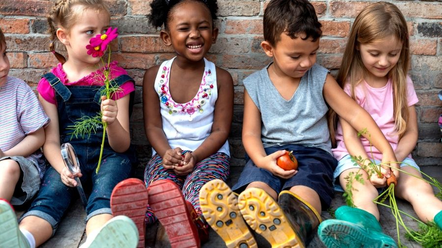 a diverse group of children sitting against a brick wall