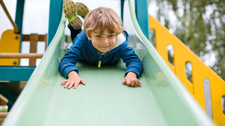 young boy sliding head first down the slide 