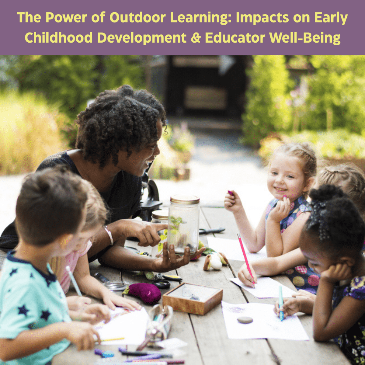 young teacher sitting outdoors at a picnic table with children crafting
