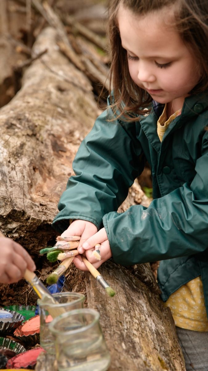 child sorting painting supplies in nature