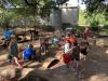 Young children playing in an outdoor sand and water area with a variety of loose parts.