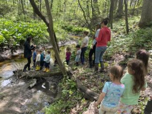 children and teachers near a stream