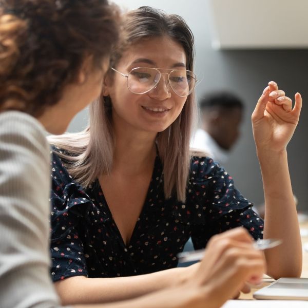 two women talking at desk