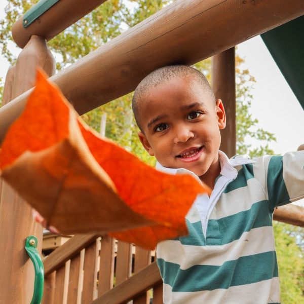 young black child playing with leaves