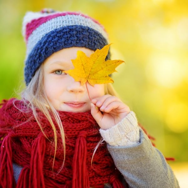 young girl hold yellow leaf over eye