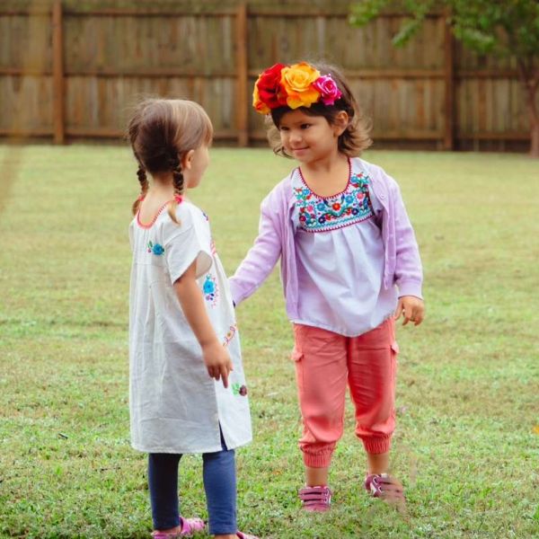 two children in cultural attire holding hands in nature