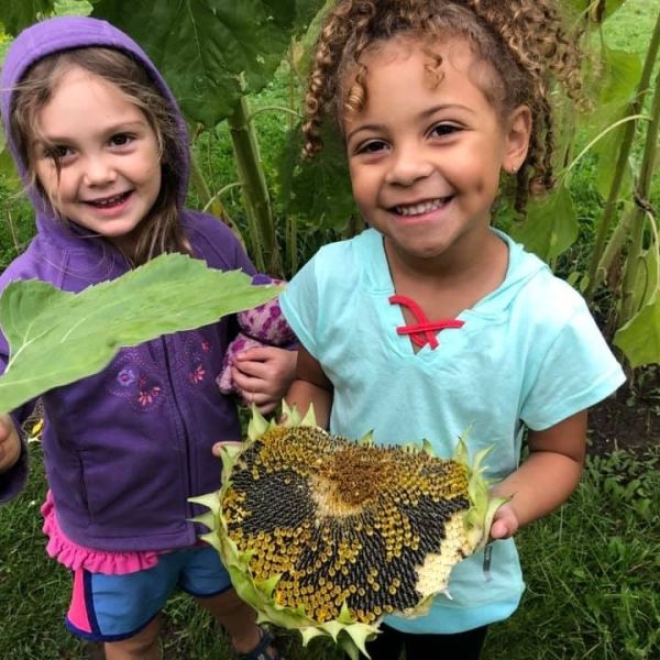 two children showing off plants in the garden