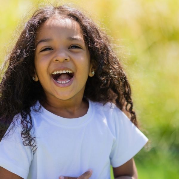 young girl smiling at camera outside