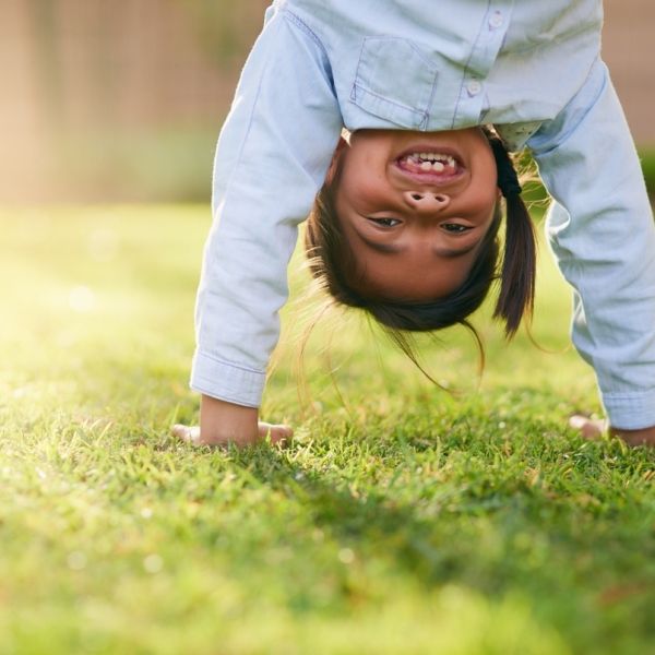 Happy, girl and handstand with grass in park