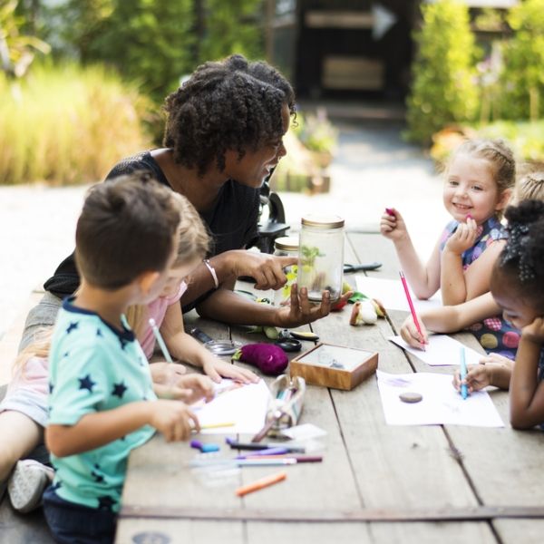 educator with group of young children outside doing artwork