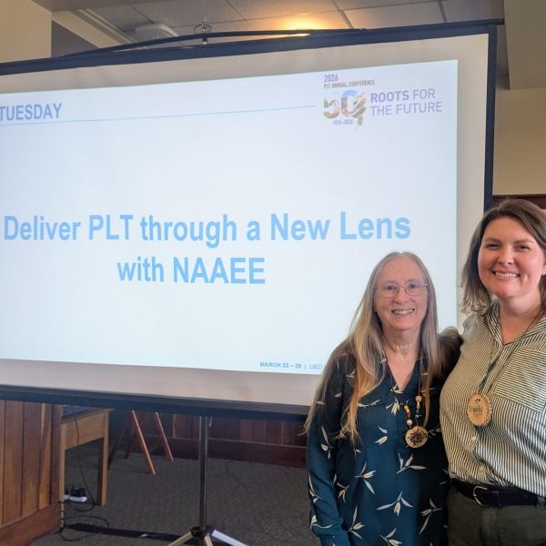 Presenters standing in front of title slide on screen