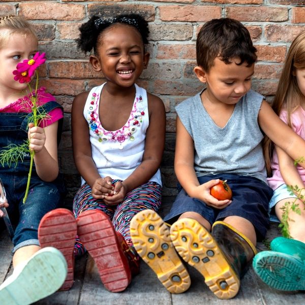 a diverse group of children sitting against a brick wall