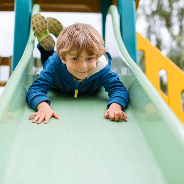young boy sliding head first down the slide 